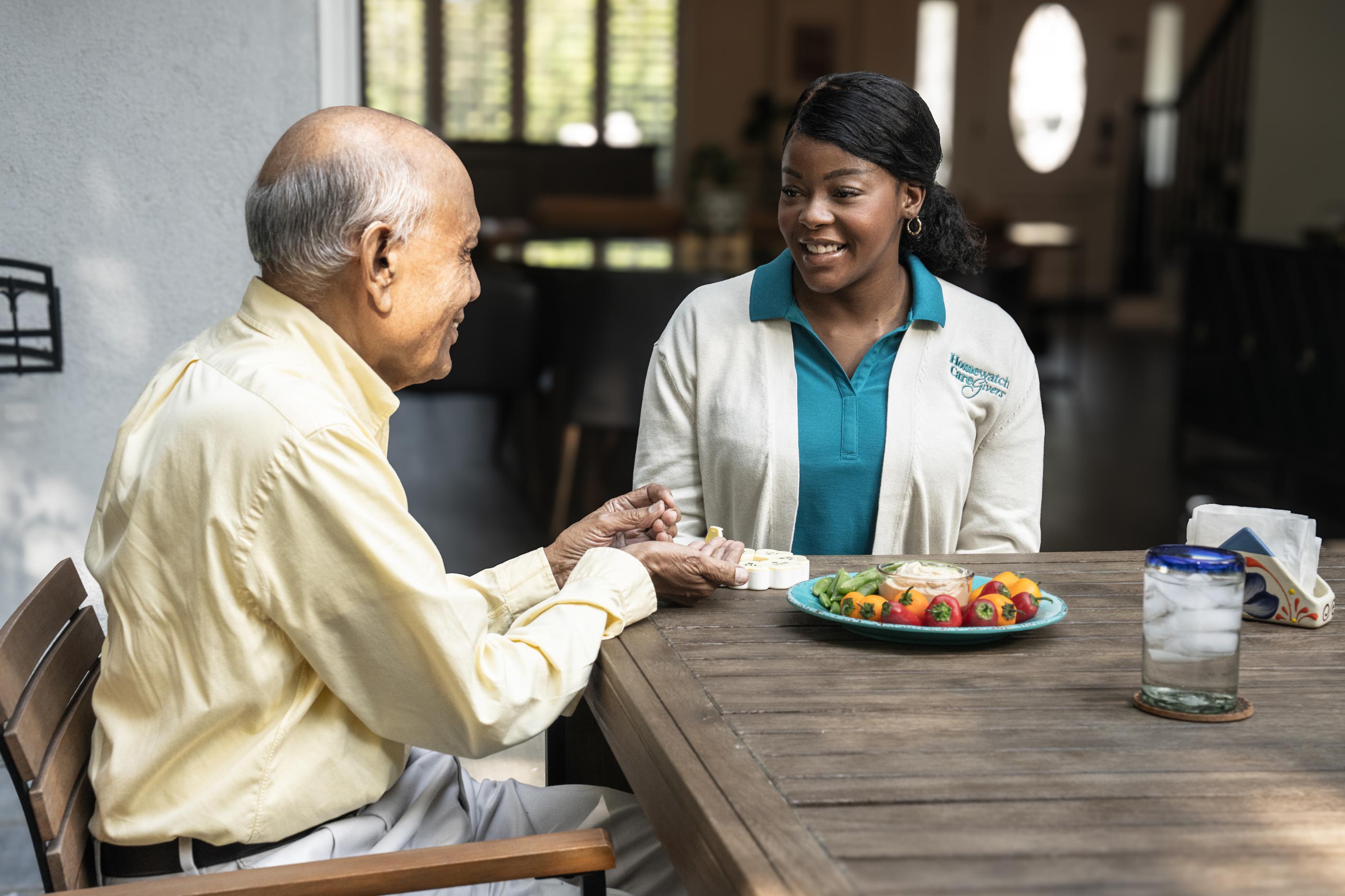 Caregiver sitting at kitchen table with older man
