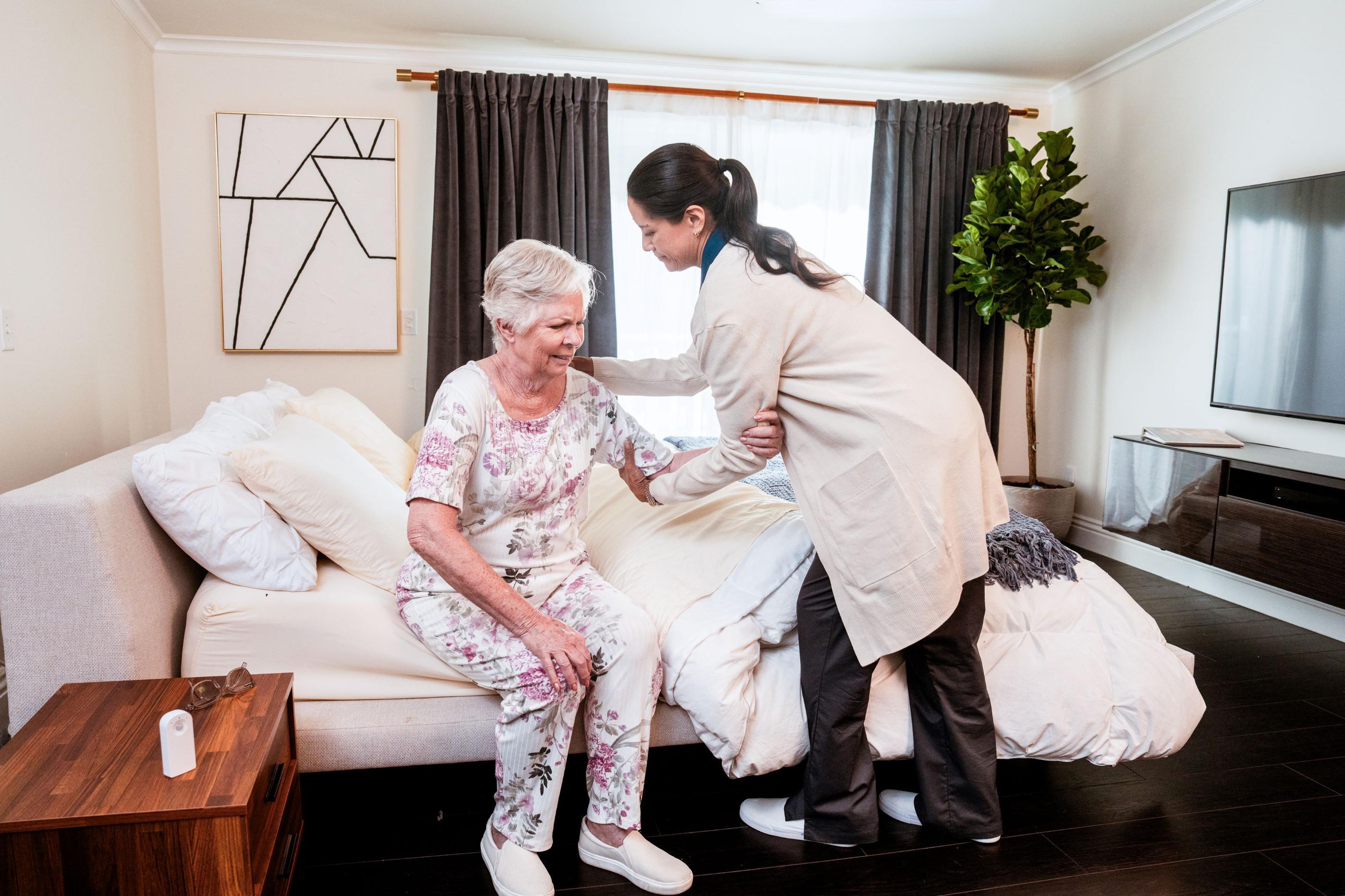 caregiver helping woman out of bed