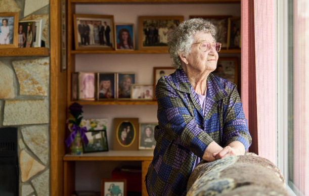 woman holding sofa and staring out window