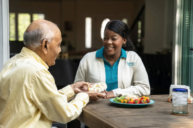 man taking pills out of container with nurse smiling at him