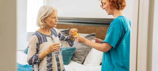 caregiver helping woman with pill bottle