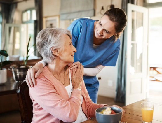 caregiver with hands on woman's shoulder smiling at her