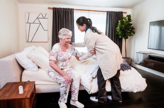 caregiver helping woman out of bed