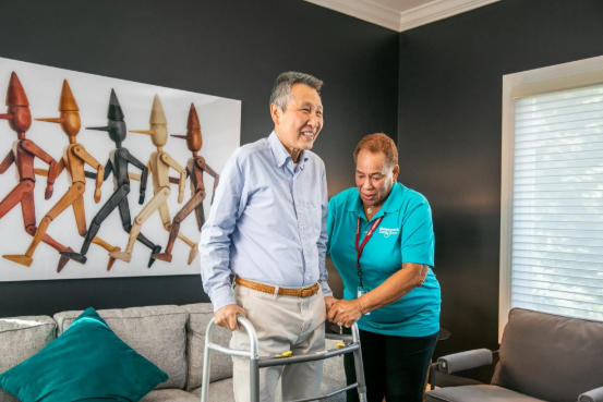 man standing with help from walker and caregiver