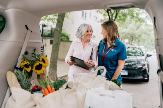 caregiver and woman with groceries in back of car