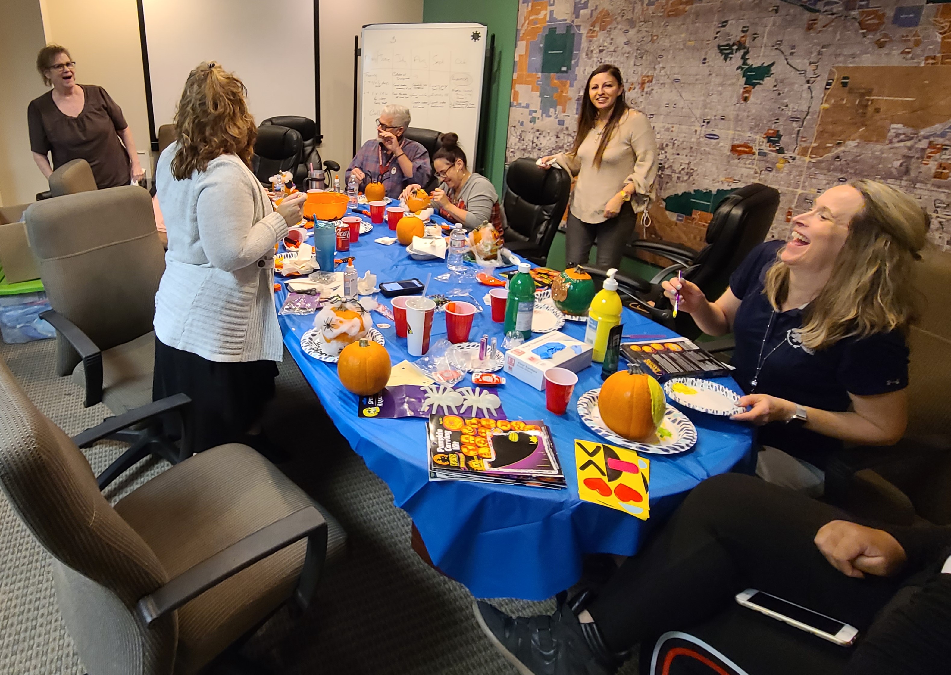 A group of people decorating pumpkins in an office setting