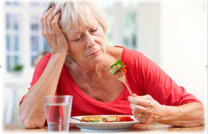 An elderly women trying to eat